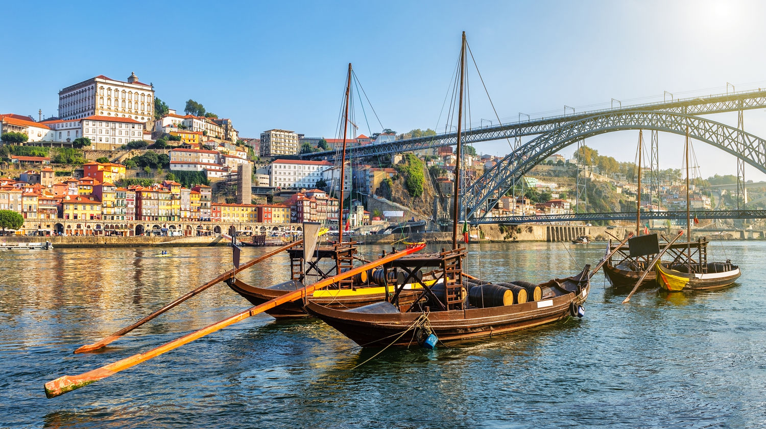 Traditional rabelo boats on the Douro River with the Dom Luís I Bridge and Porto’s Ribeira district in the background