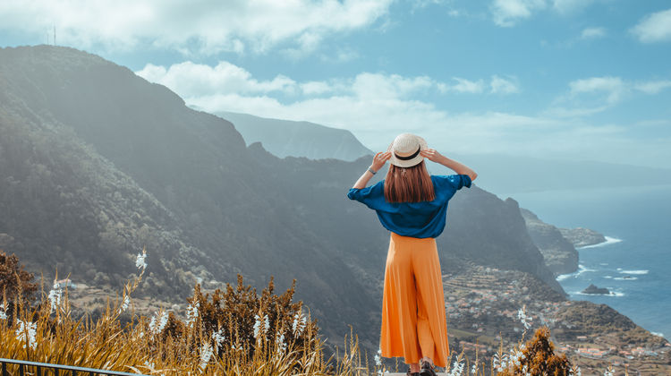 A traveler admiring Madeira’s dramatic mountain scenery from a high viewpoint under a clear blue sky.