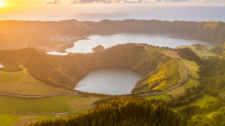 Aerial view of the Sete Cidades caldera showing Lagoa Azul and the green Lagoa de Santiago surrounded by volcanic cliffs on São Miguel Island.