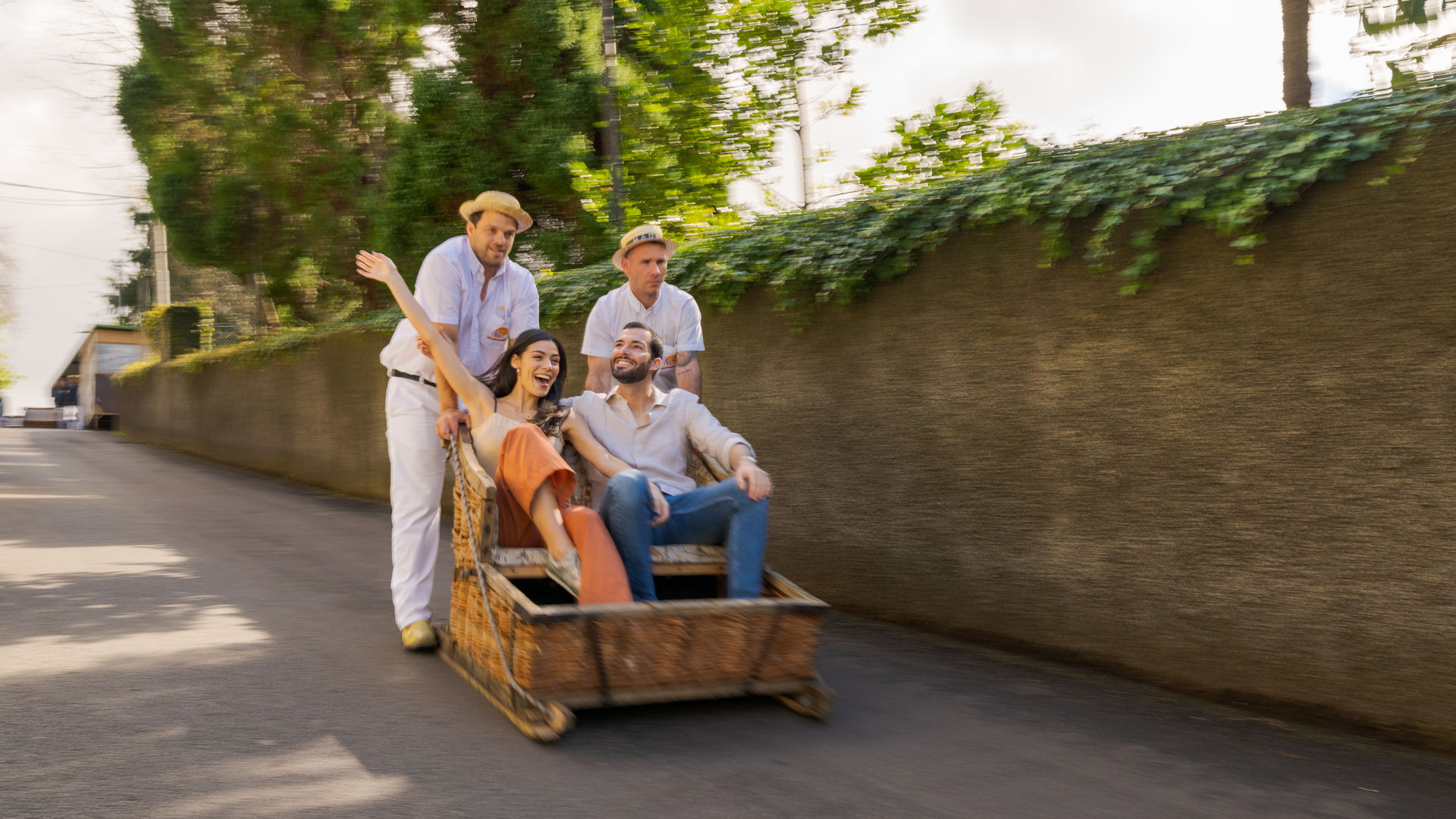 Couple enjoying the famous wicker toboggan ride in Funchal, Madeira, Portugal, guided by two carreiros down the steep streets — one of the island’s most iconic cultural experiences.