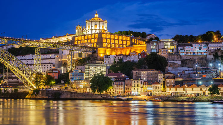 Night view of Vila Nova de Gaia and Porto skyline illuminated along the Douro River in Portugal
