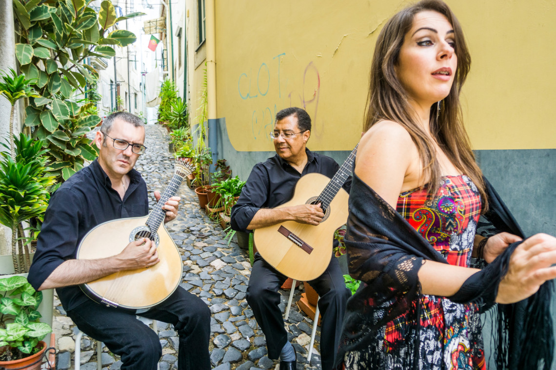 Musicians playing Fado music in a charming Lisbon street, capturing the essence of a getaway in Portugal with cultural and vibrant experiences.