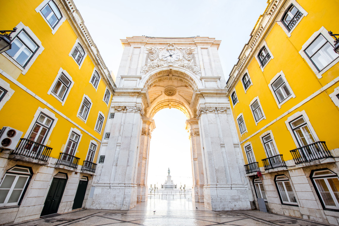 View of the Rua Augusta Arch in Lisbon, Portugal, framed by yellow buildings and opening onto Praça do Comércio.