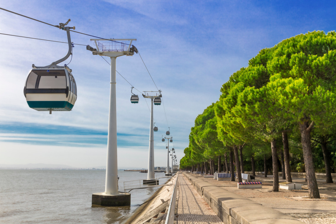 Cable car gliding over Park das Nações Unidas with Lisbon's skyline in the distance.