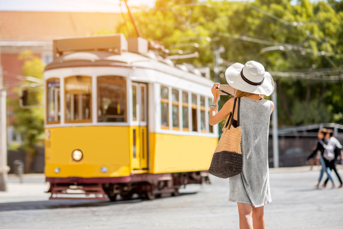 Vintage yellow tram gliding through the historic streets of Lisbon, Portugal, a popular mode of travel for tourists.