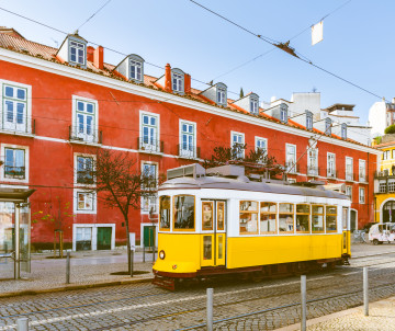 Iconic yellow tram passing through a historic street in Lisbon, Portugal, a top highlight included in Lisbon Black Friday travel deals and vacation packages.