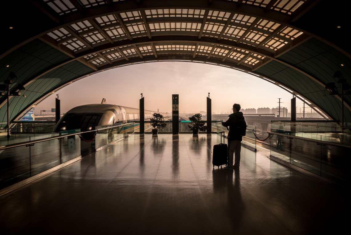 High-Speed Train Travel in Portugal & Europe Traveler with luggage waiting at a modern high-speed train station, with a sleek train ready for departure at sunrise.