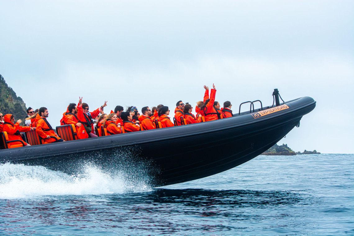 Group of people in orange jackets enjoying a high-speed RIB boat tour with AG Expeditions off the coast of São Miguel Island, Azores.
