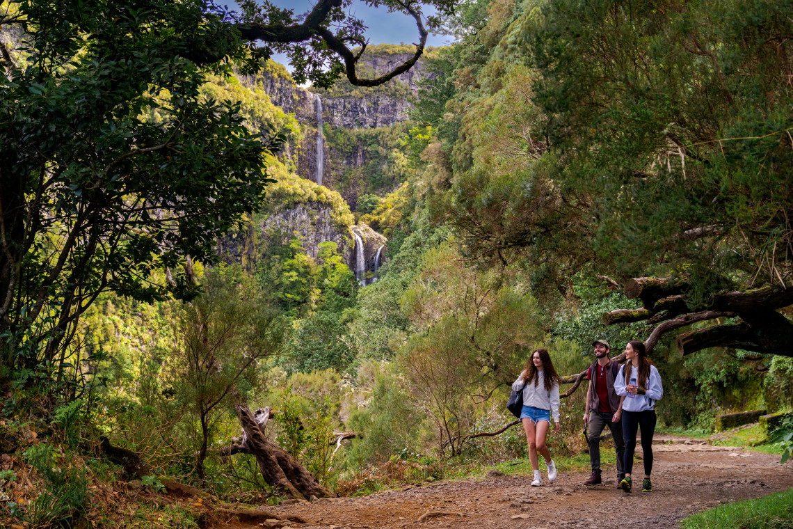 Levada Walk and Waterfall Hike – Madeira Island Nature Trail Group of hikers walking through lush forest near a waterfall on a levada trail in Madeira Island, Portugal