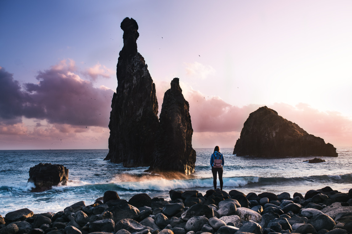 Beautiful coast view during a sunset with young man standing against rocks
