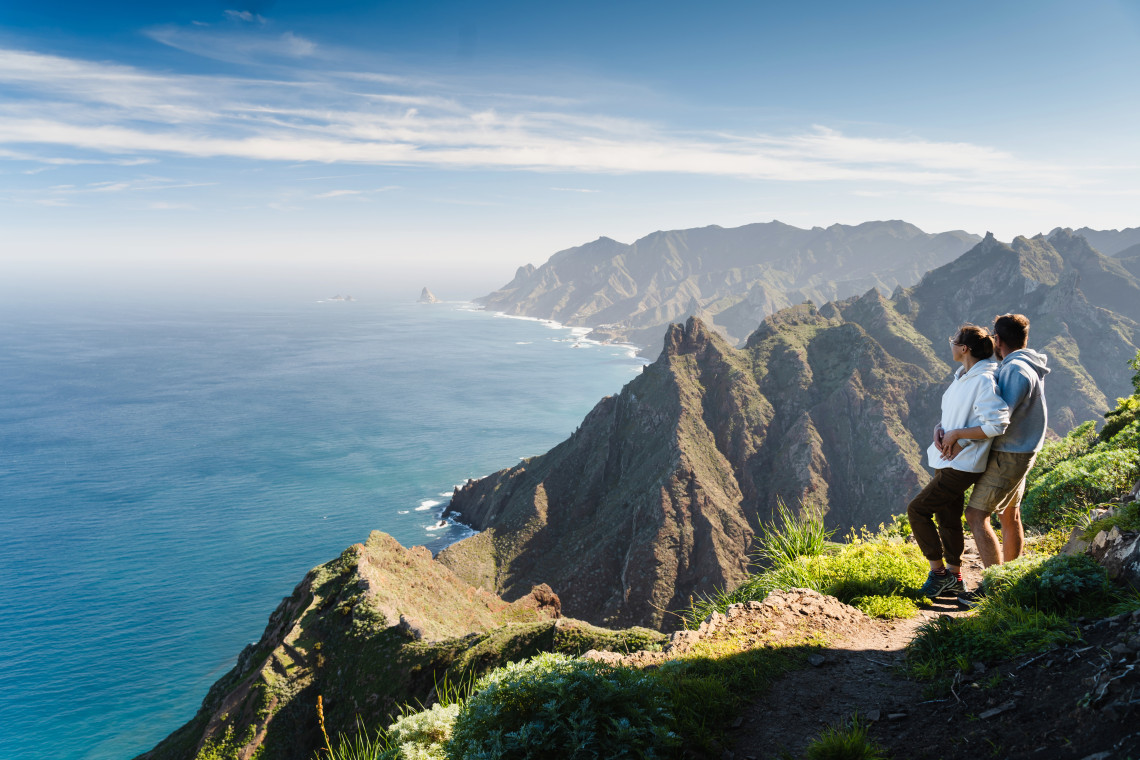 Couple admiring the dramatic cliffs and Atlantic Ocean from a viewpoint in Madeira, Portugal.