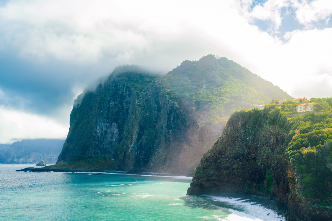 Towering green cliffs rising above the Atlantic Ocean along Madeira’s rugged north coast, Portugal.