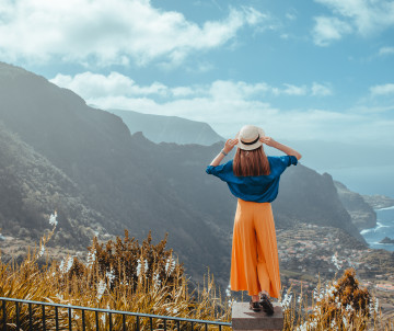 Woman enjoying panoramic mountain and ocean views in Madeira, Portugal, a top highlight of Black Friday travel deals.