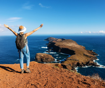 woman enjoying beautiful view to ocean and cliffs on Ponta de Sao Lourenco hiking trail in Madeira island. Portugal