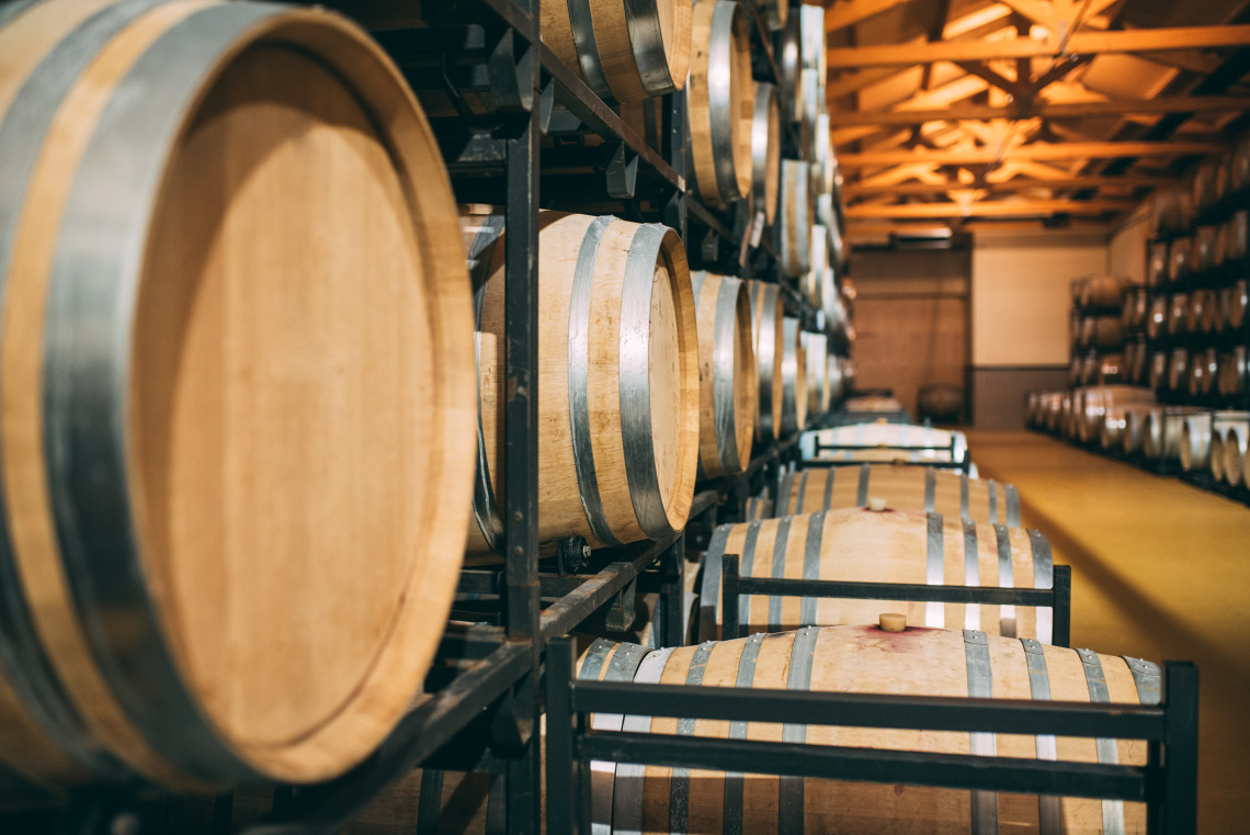 Interior of a wine cellar in Portugal with rows of wooden barrels used for aging wine, showcasing traditional winemaking methods.