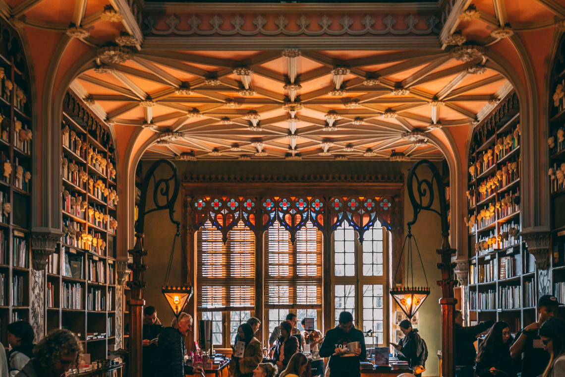 Interior of Livraria Lello in Porto, Portugal, with neo-Gothic architecture, stained glass windows, and visitors exploring one of the world’s most beautiful bookstores.