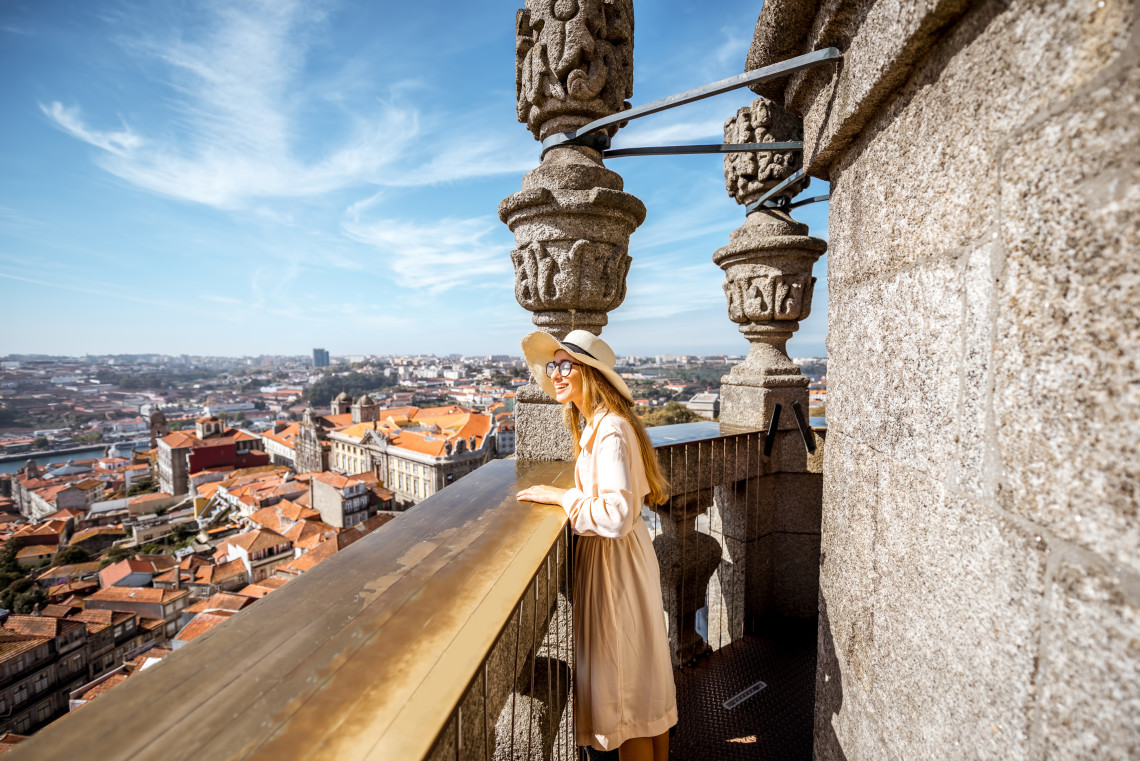 Traveler enjoying panoramic views over Porto’s red rooftops and Douro River from the historic Clérigos Tower.
