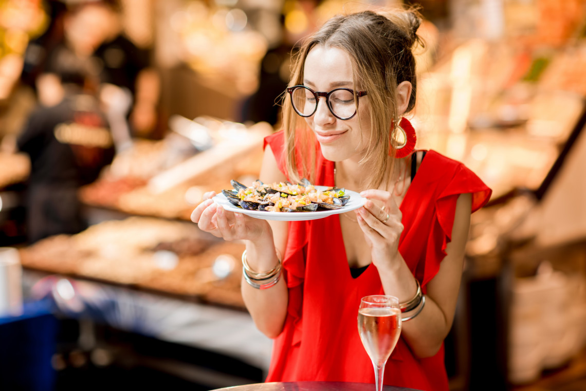 Enjoy The Best of Barcelona Food, Spain woman-eating-mussels-at-the-food-market-barcelona-spain