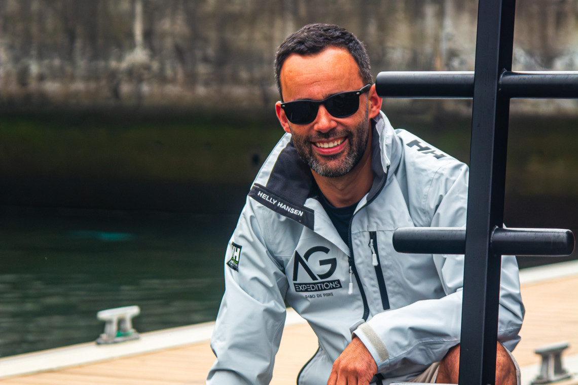 Luís Nunes, founder of AG Expeditions, smiling at the dock in São Miguel Island, Azores, wearing the official expedition jacket.