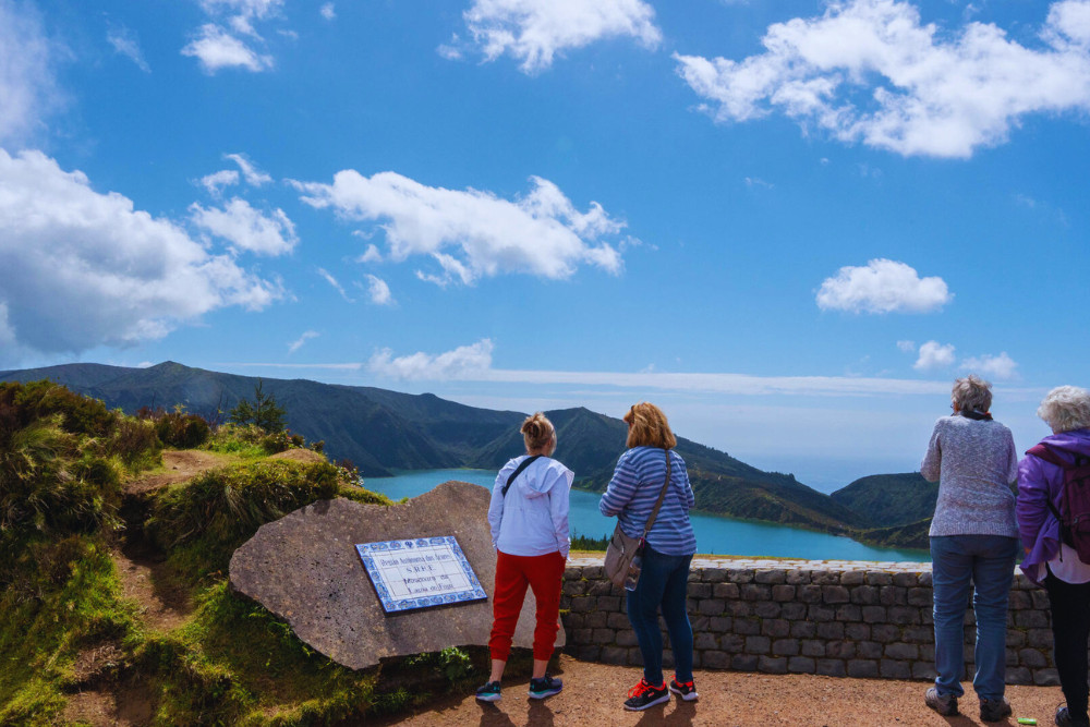 Group Tour Viewing Lagoa do Fogo – São Miguel Island, Azores A group of travelers enjoying panoramic views of Lagoa do Fogo, a crater lake surrounded by mountains on São Miguel Island in the Azores, a must-see on guided group tours.