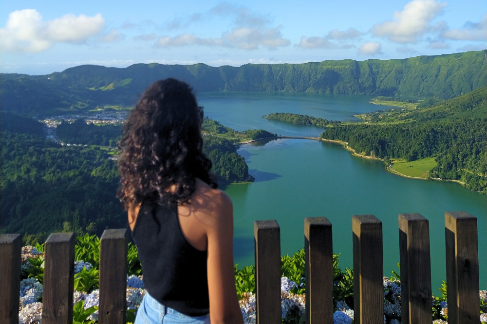 Sete Cidades Scenic Viewpoint in São Miguel, Azores Woman admiring the twin crater lakes of Sete Cidades from Vista do Rei viewpoint, Azores, surrounded by lush volcanic landscapes.
