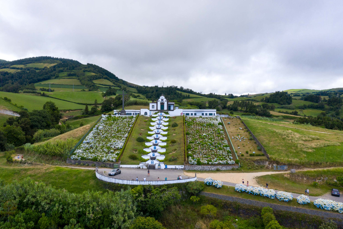 Chapel of Nossa Senhora da Paz in São Miguel – A Religious Landmark in Vila Franca do Campo, Azores Aerial view of the Chapel of Nossa Senhora da Paz and its symbolic staircase, surrounded by green hills and hydrangeas in Vila Franca do Campo, São Miguel Island, Azores.
