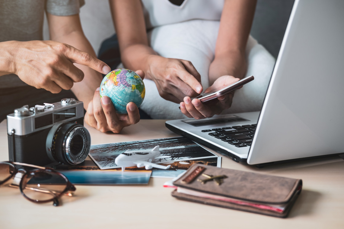 Couple planning a trip using a laptop, globe, and travel essentials on a desk