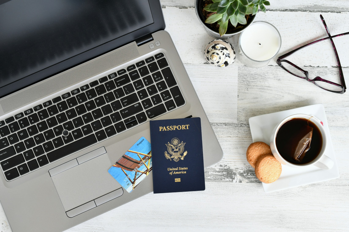 U.S. passport and travel documents on a laptop beside tea and cookies