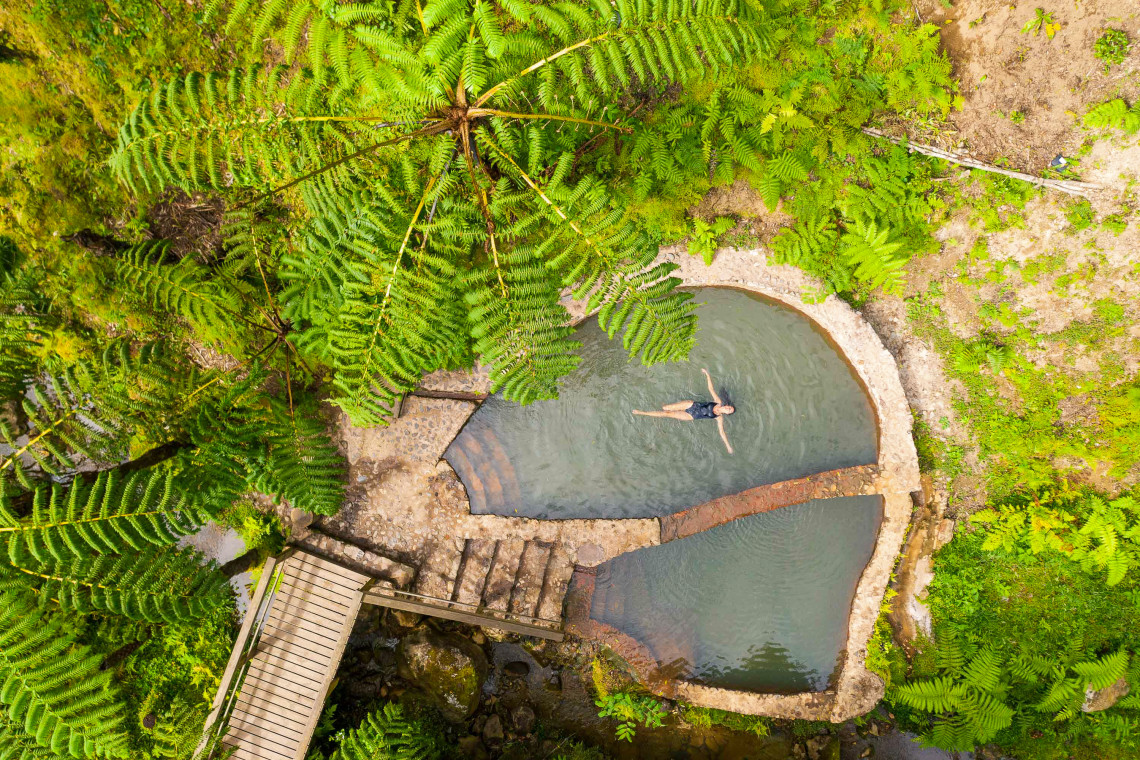 Woman relaxing in a natural thermal pool at Caldeira Velha, São Miguel Island, Azores
