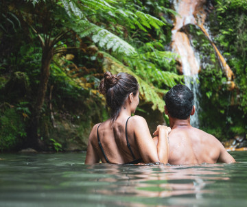 Relaxing in the Natural Hot Springs of Caldeira Velha, São Miguel Island Couple enjoying the thermal waters and waterfall at Caldeira Velha in São Miguel, Azores