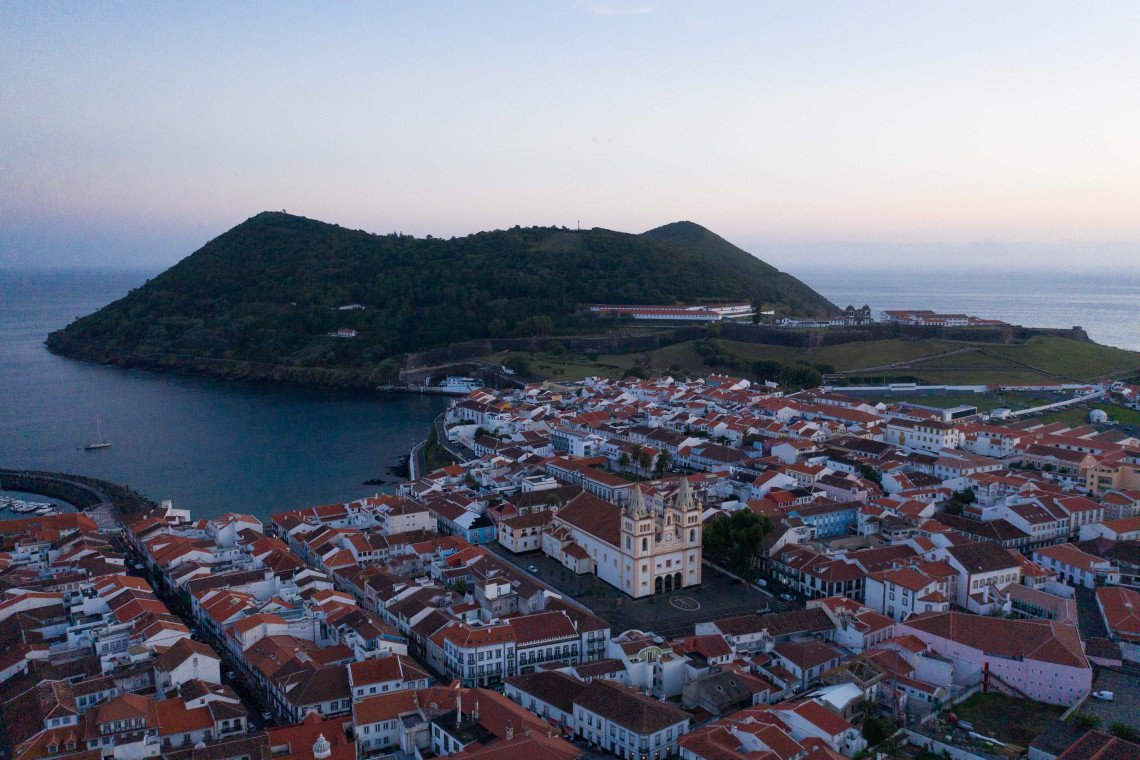 Aerial view of Angra do Heroísmo and Monte Brasil at sunset on Terceira Island, Azores, showcasing the historic city and coastal landscape
