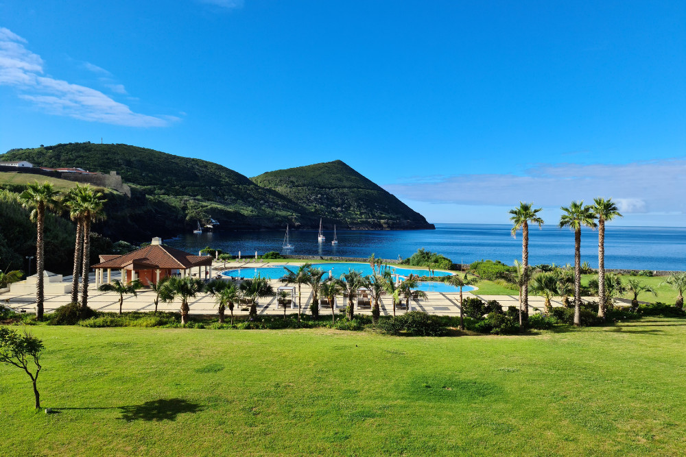 Oceanfront hotel with pool and palm trees overlooking the bay near Angra do Heroísmo on a sunny day, Terceira Island, Azores