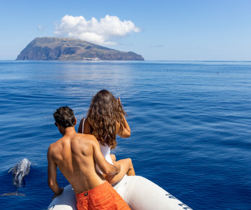 A couple on a boat admiring the ocean and island landscape in the Azores