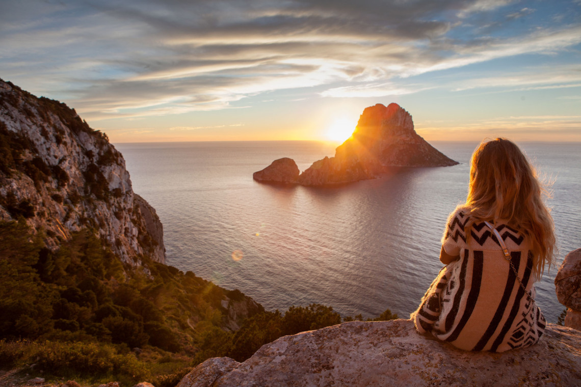 Sunset in Es Vedra Beach, Ibiza Island, Spain woman-back-to-the-front-watching-a-beautiful-sunset-at-the-beach-the-beach-is-called-es-vedra-in-ibiza-and-belongs-to-balearic-islands-in-spain