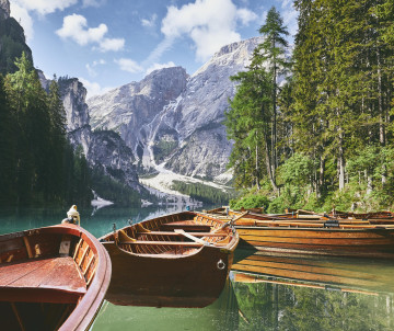 The dolomites, italy Beautiful dolomite mountains, lake with boats and trees