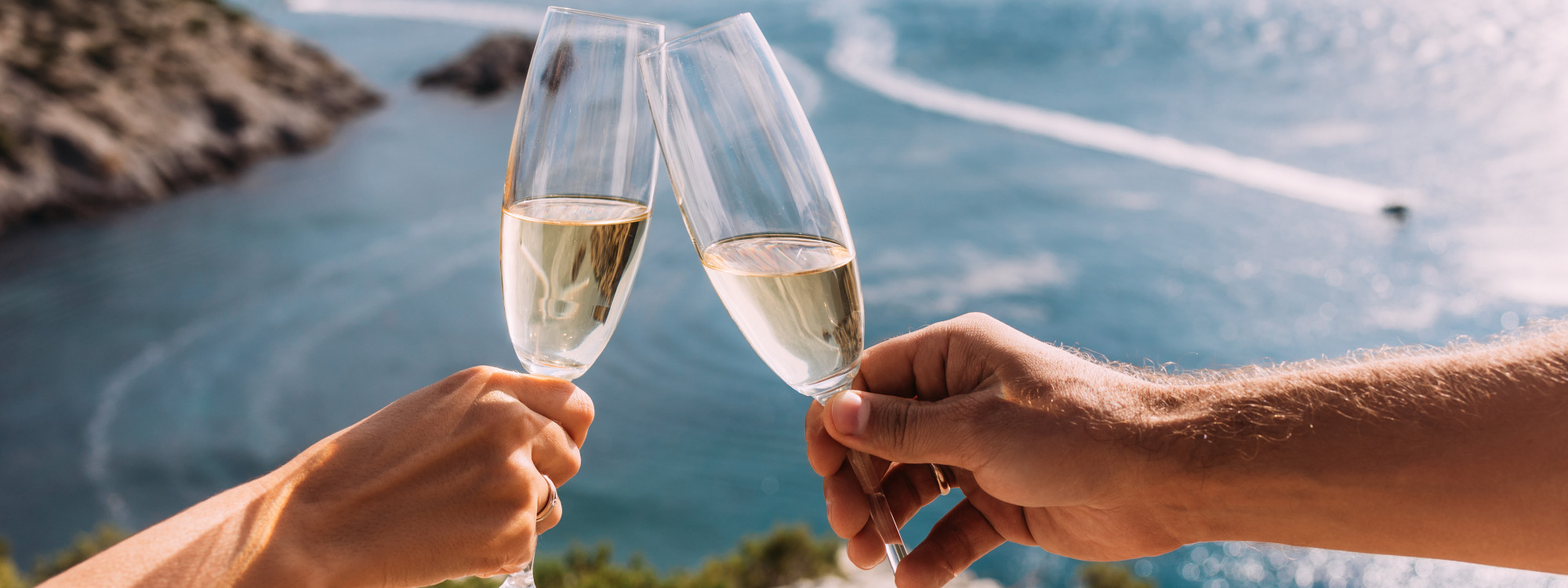 A couple toasting with champagne glasses on the Algarve coast, celebrating with ocean views during a Black Friday travel package deal in Portugal