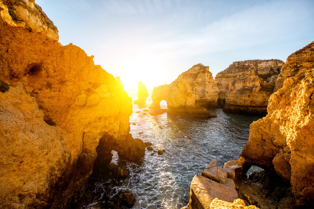 Dramatic sea cliffs and natural rock arches at Ponta da Piedade in Lagos, Algarve, Portugal, illuminated by golden sunset light over the Atlantic Ocean