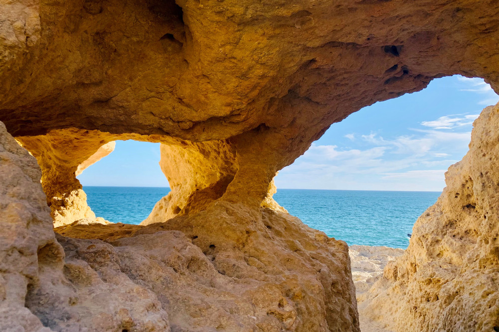 View of the Atlantic Ocean through natural rock arches at Algar Seco in Carvoeiro, Algarve, Portugal, with weathered limestone framing the sea and sky